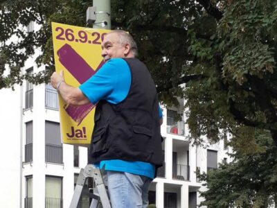 Mitglied der MieterWerkStadt Charlottenburg befestigt ein Plakat für den Volksentscheid „Deutsche Wohnen & Co enteignen“.